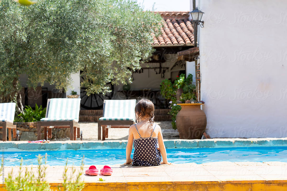 Little girl sitting at pool in summer