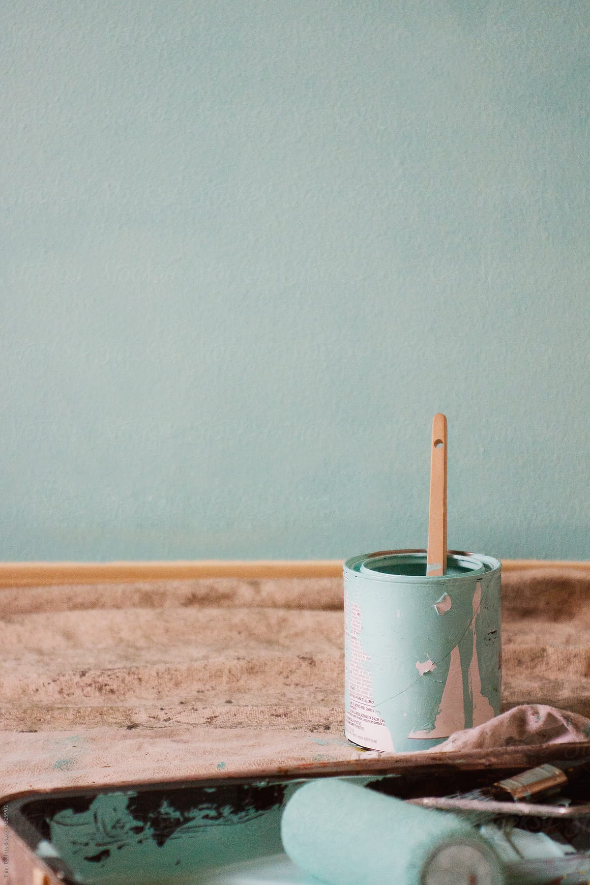 Paint brush in paint can on floor by finished wall