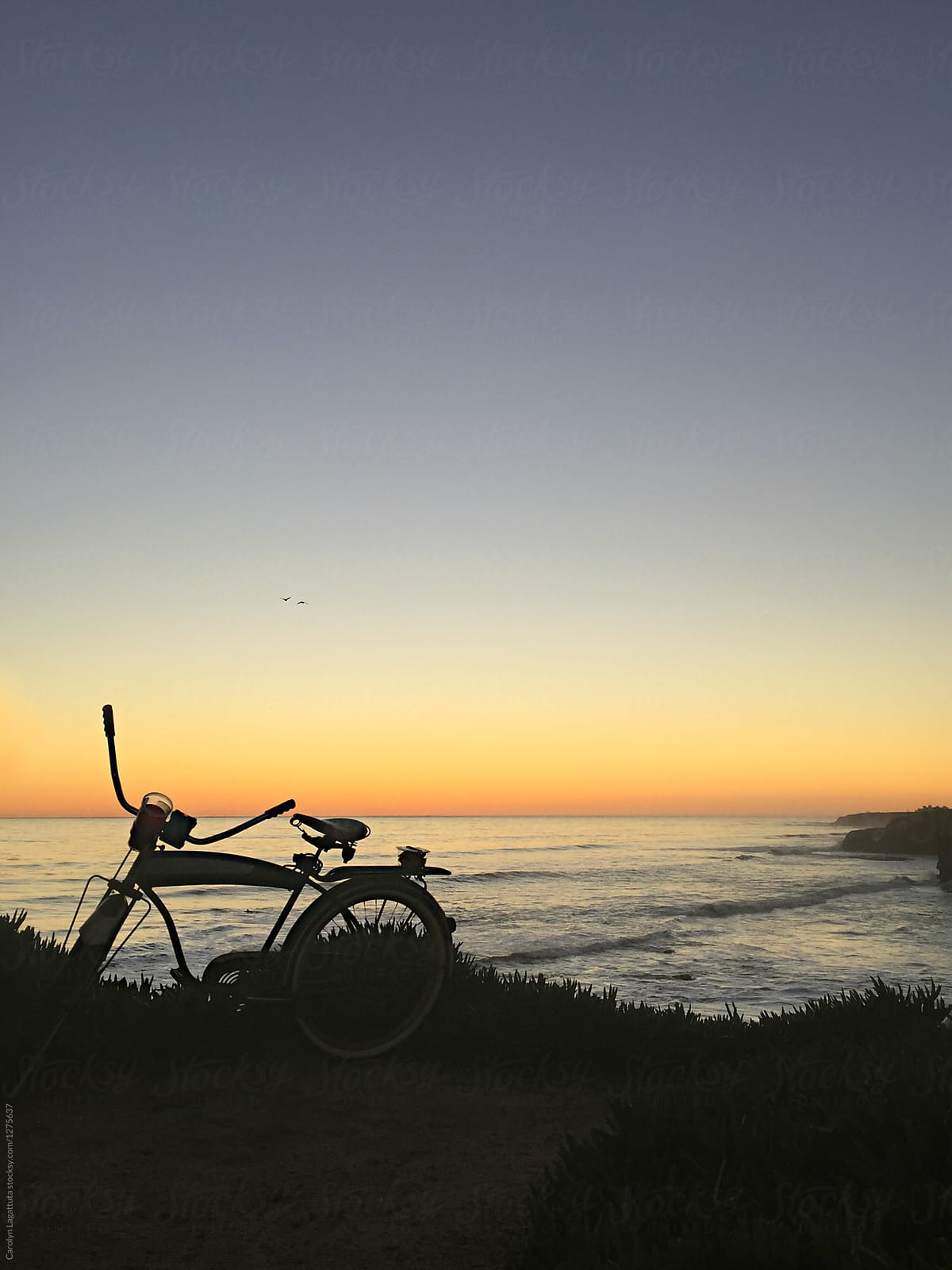 Cruiser bike parked by the ocean at sunset