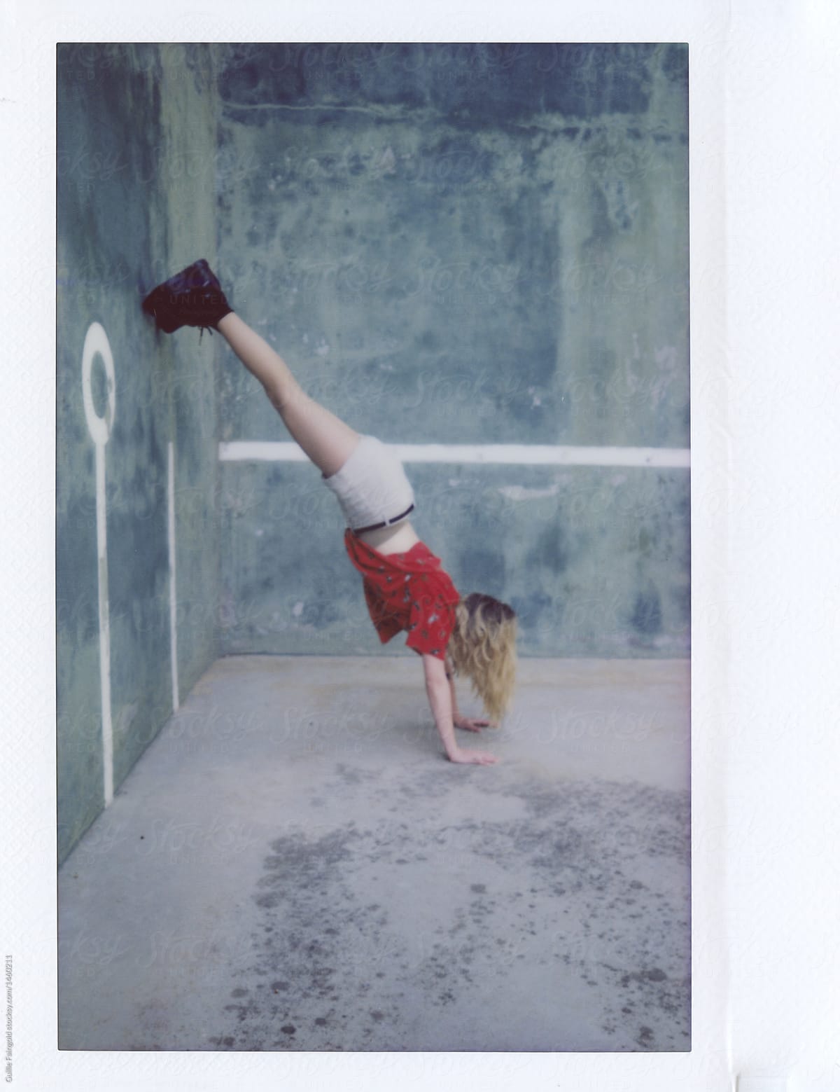 Girl standing on arms with legs on wall.