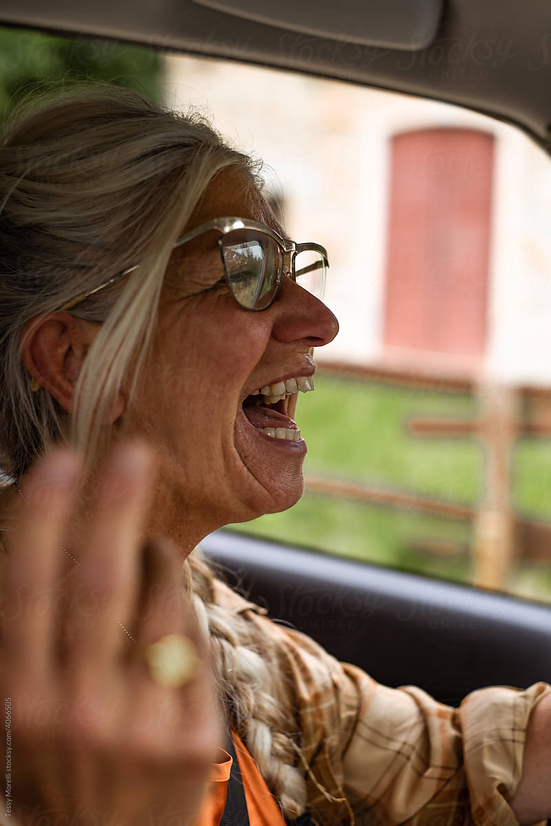 Senior woman in her car singing on a road trip