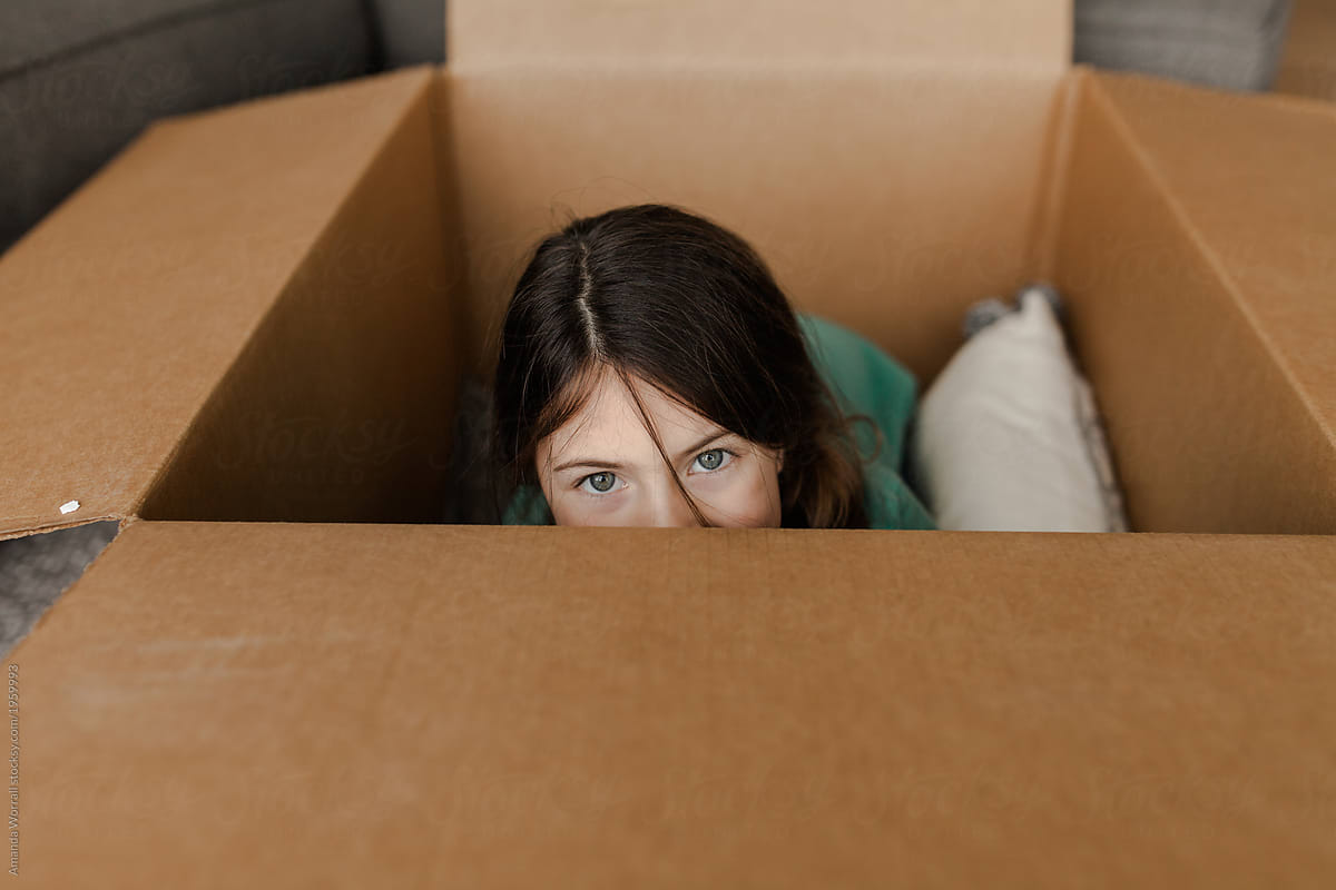 Girl peeking out from inside of a large box