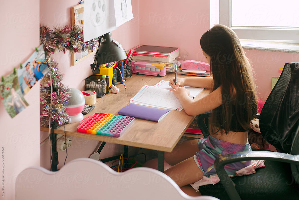 A girl does her homework sitting at a desk
