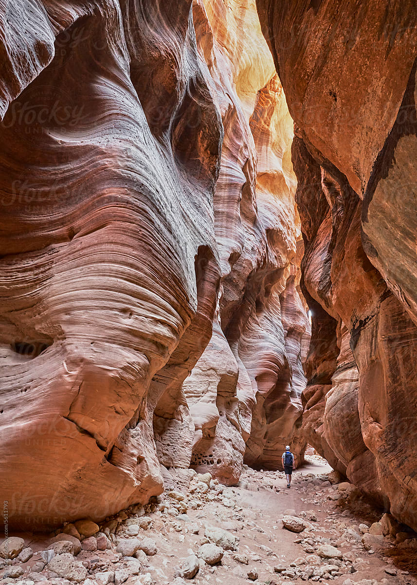 Man hiking within the undulating rock formations of Bulkskin Gulch