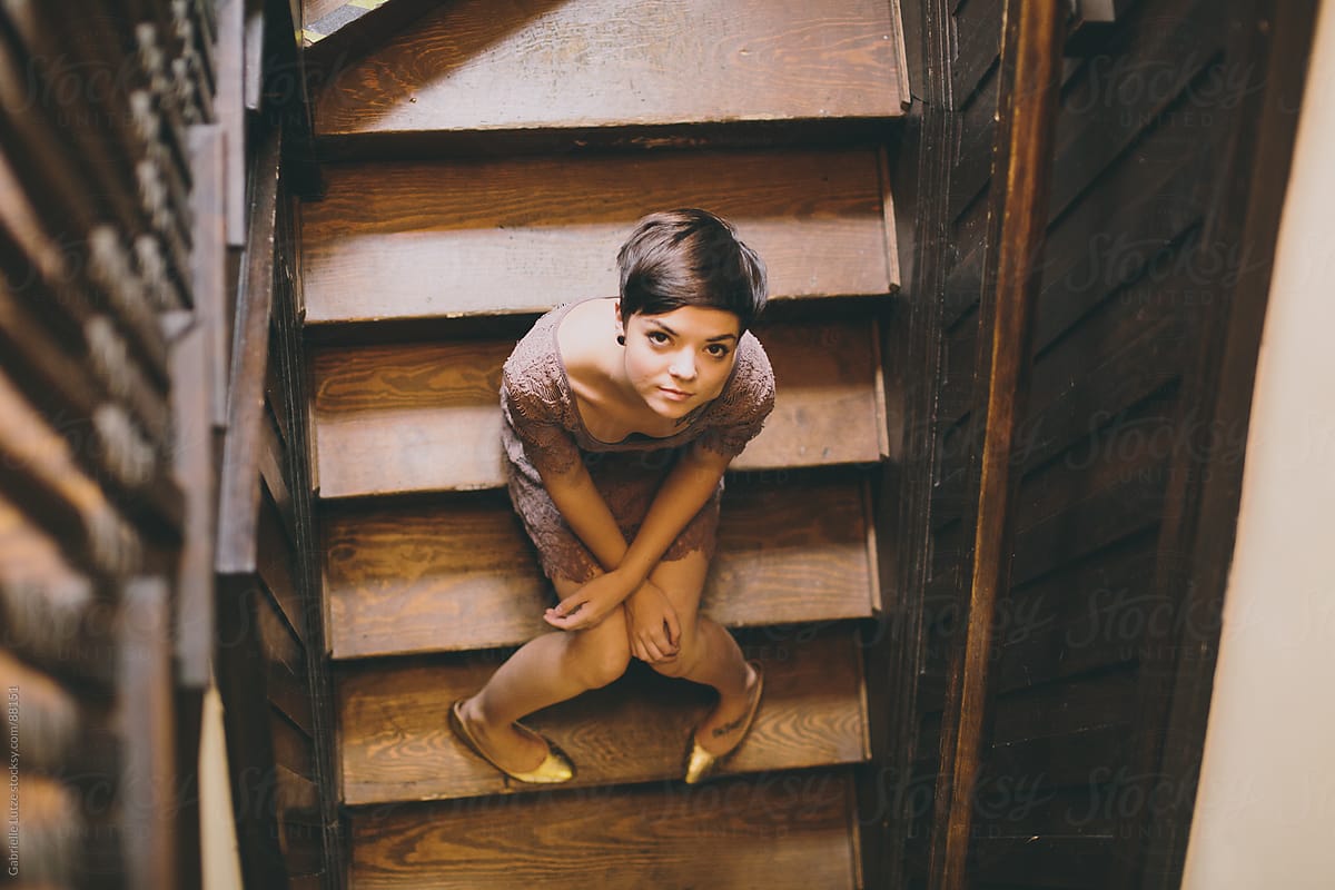Girl sitting on wood stairs looking up
