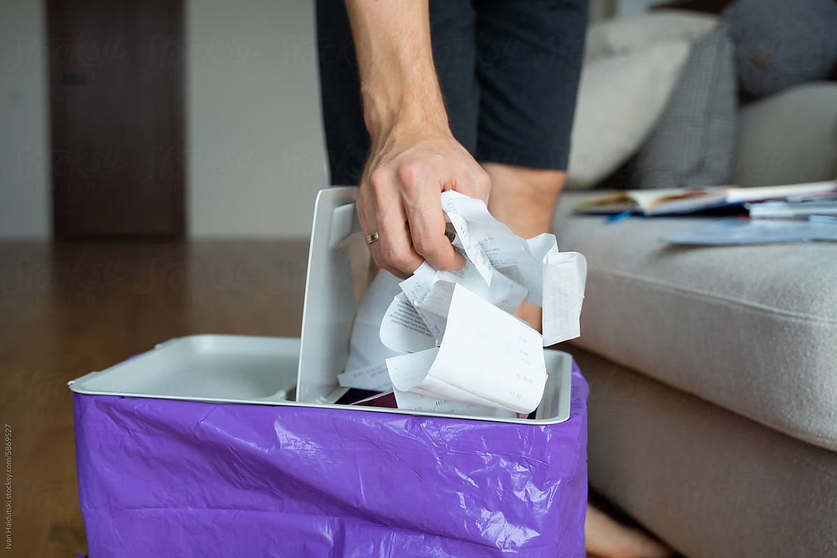 Man throwing receipts into Waste Basket, organizing home office