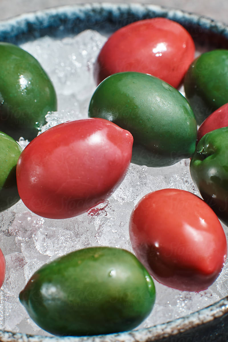 fresh olives on a plate with ice in a ceramic plate on a stone background