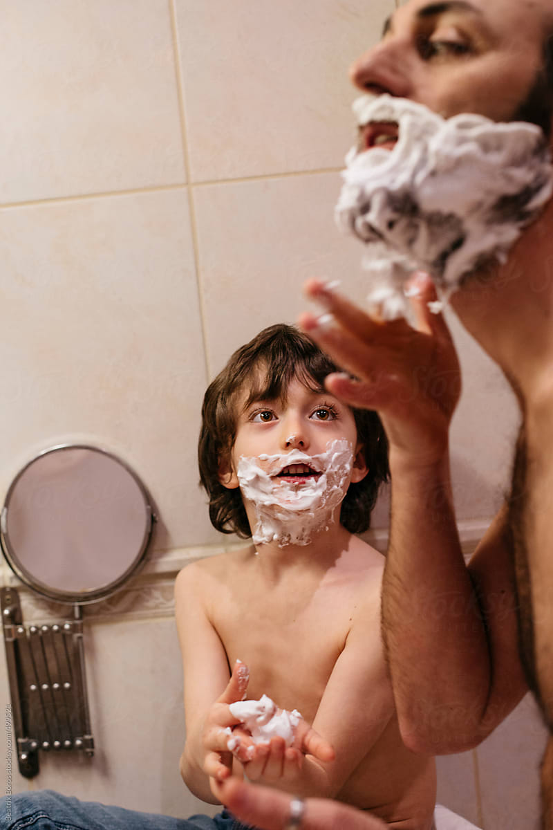 6 years old boy looking at his father as a role model while he is shaving