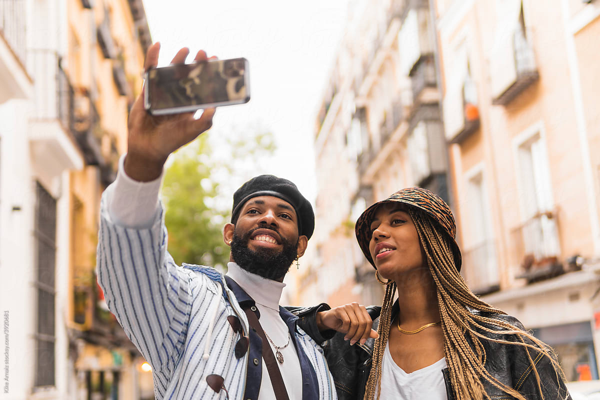 Stylish black couple taking selfie in town
