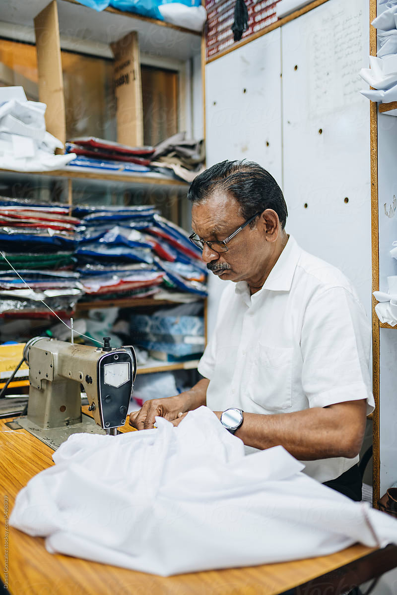 Professional Indian tailor sewing shirt on machine