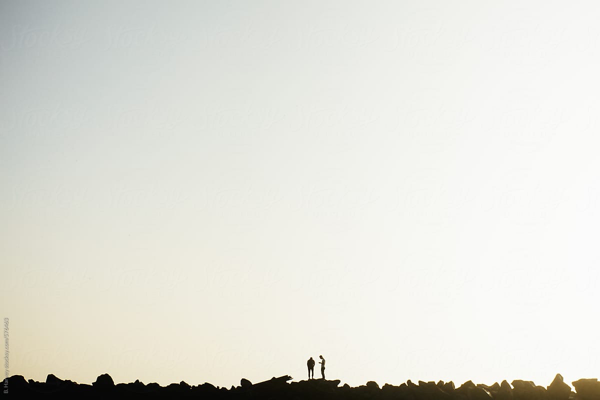 Two Friends Silhouetted on Rocks at Sunset