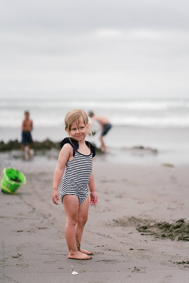 little girl in blue and white striped swim suit with braid down her back on the beach