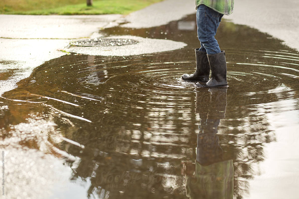 Child in boots walks through puddle