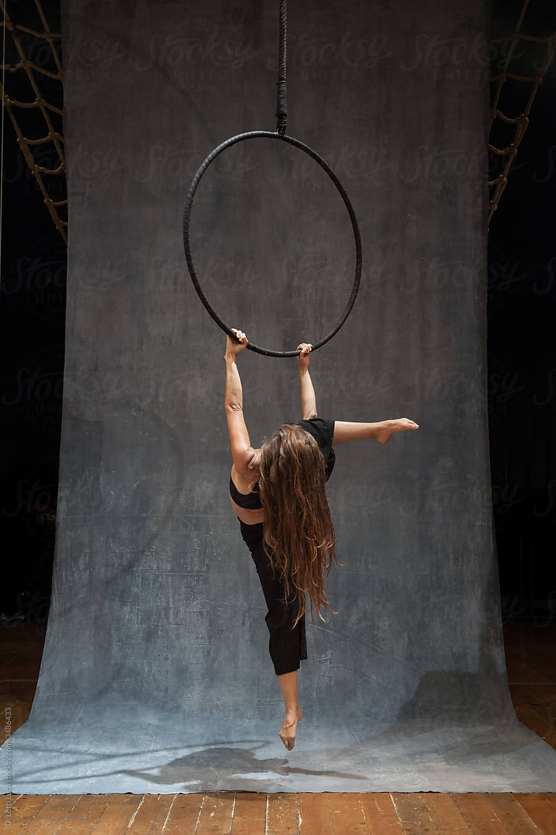 Full body of female aerialist in dress performing cross pose on aerial hoop  during rehearsal against light background in studio Stock Photo - Alamy