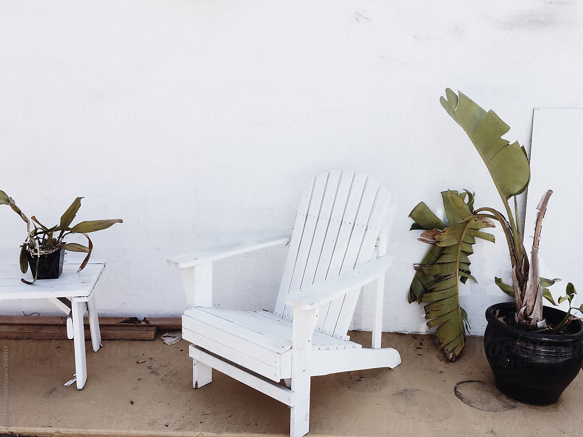 white chair outside white wall with plants