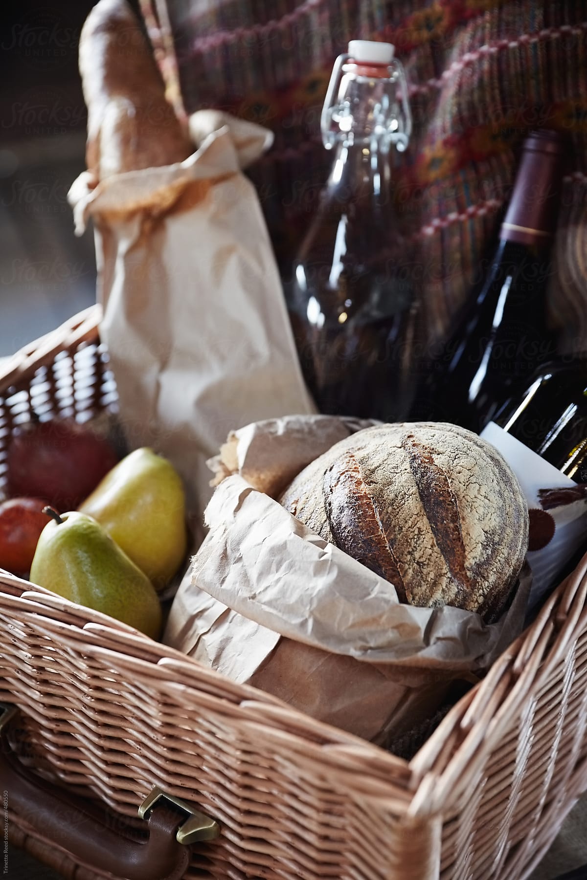 Bread, wine, and fruit in rustic woven picnic basket