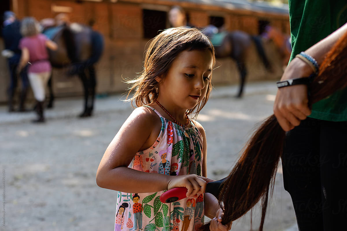 little girl brushing horse tail