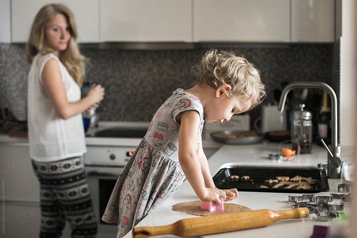 Little girl baking cookies with her mom