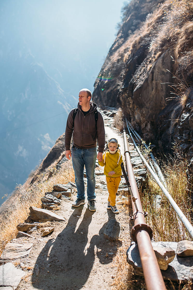 A father and son hike on a high narrow path