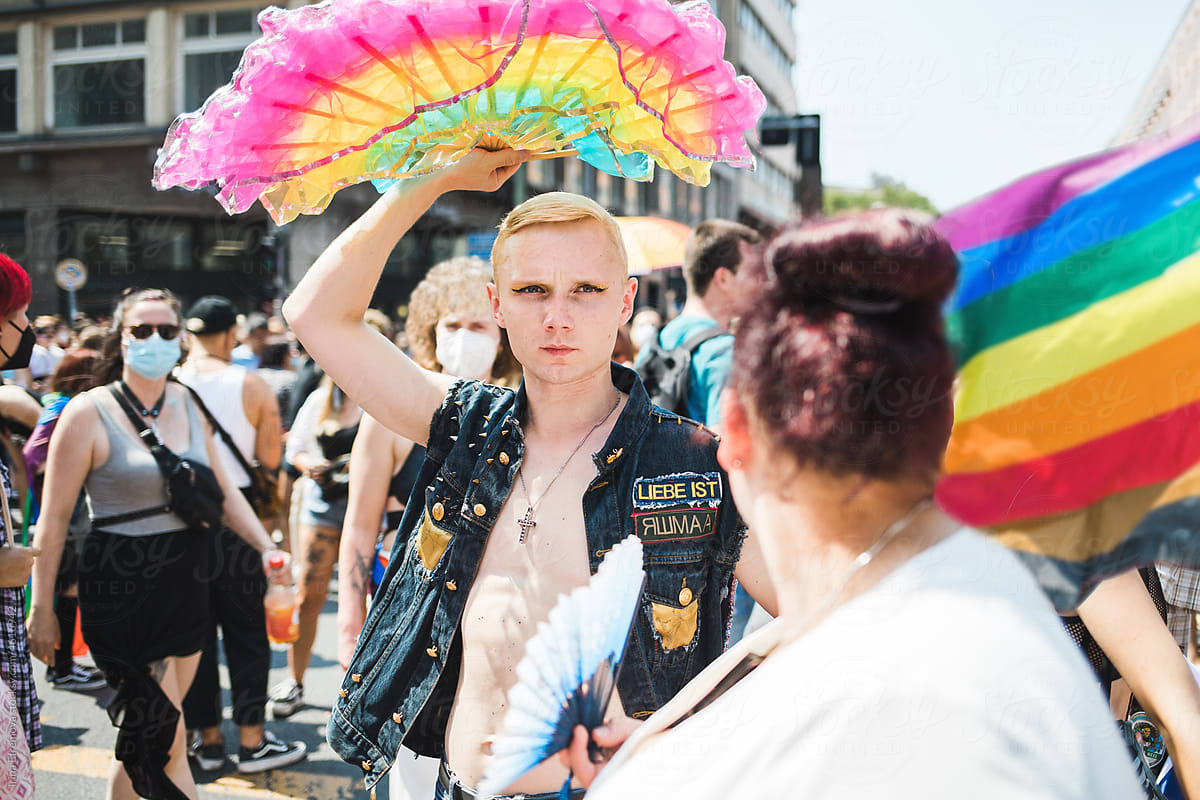 Man holds rainbow handheld fan up on a Pride