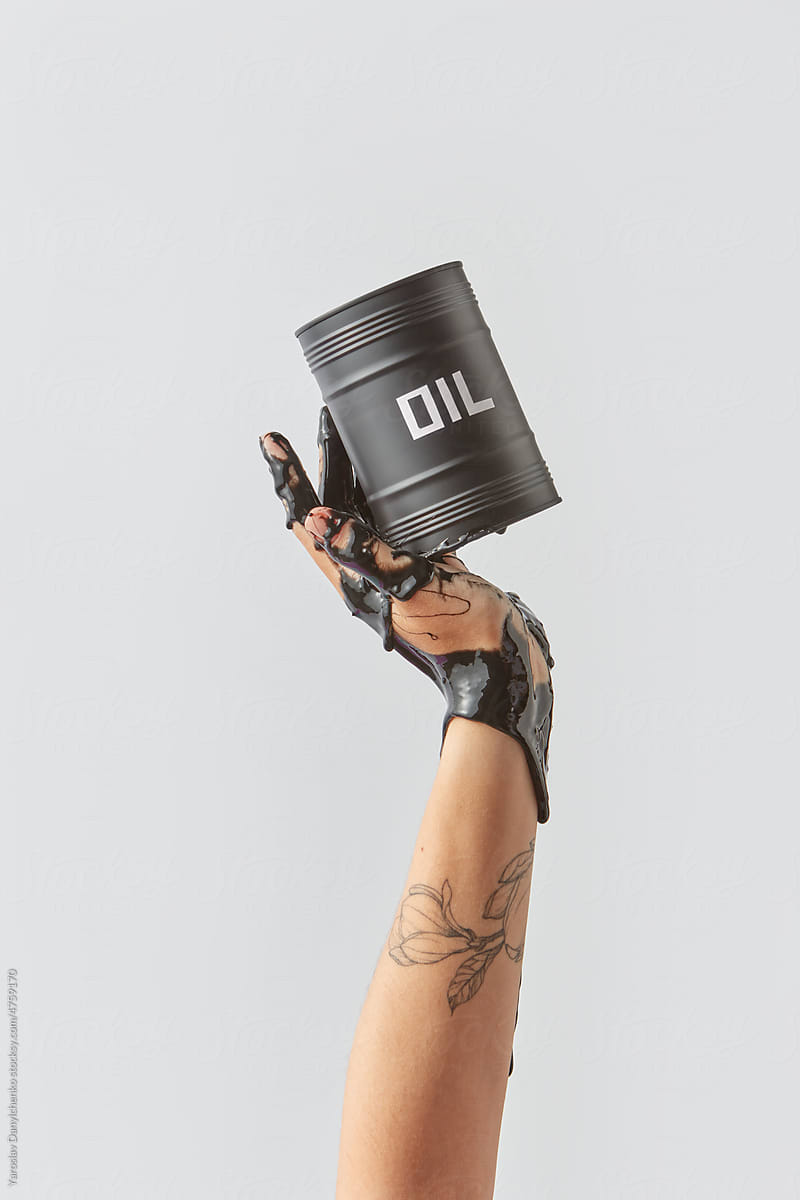 Woman holding black barrel with spilled oil.