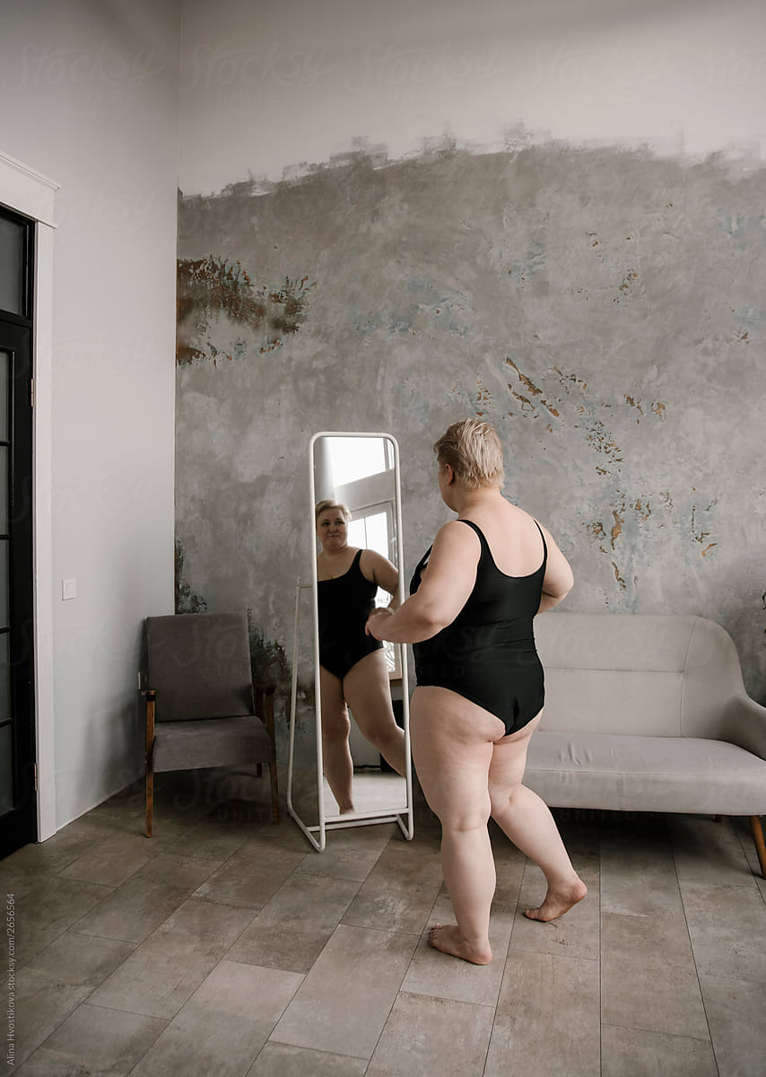 Blonde woman looking at reflection in mirror.