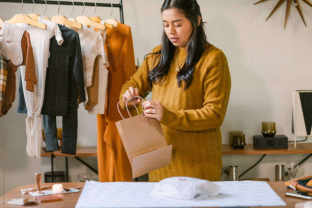 Small business owner packaging clothing in atelier