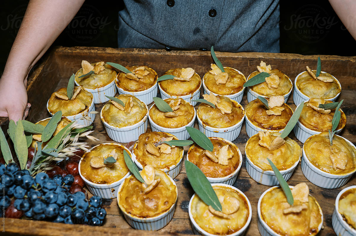 individual pot pies held by chef at dinner party at night