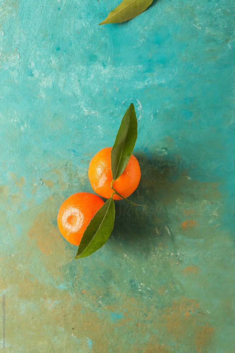 Fresh ripe tangerines with green leaves on a turquoise abstract background