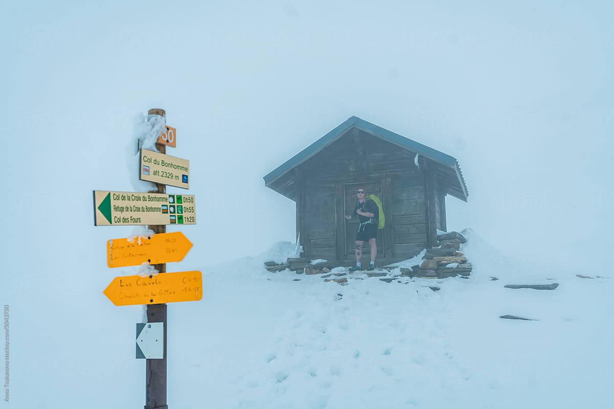 Man sheltering near the alpine hut during heavy snowstorm in mountains