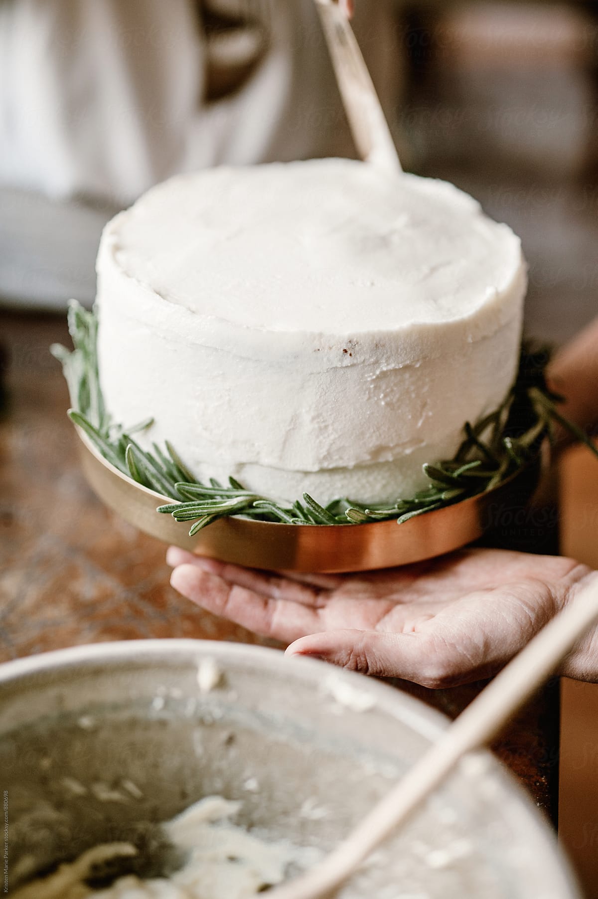 Females decorate homemade cake with white icing and rosemary