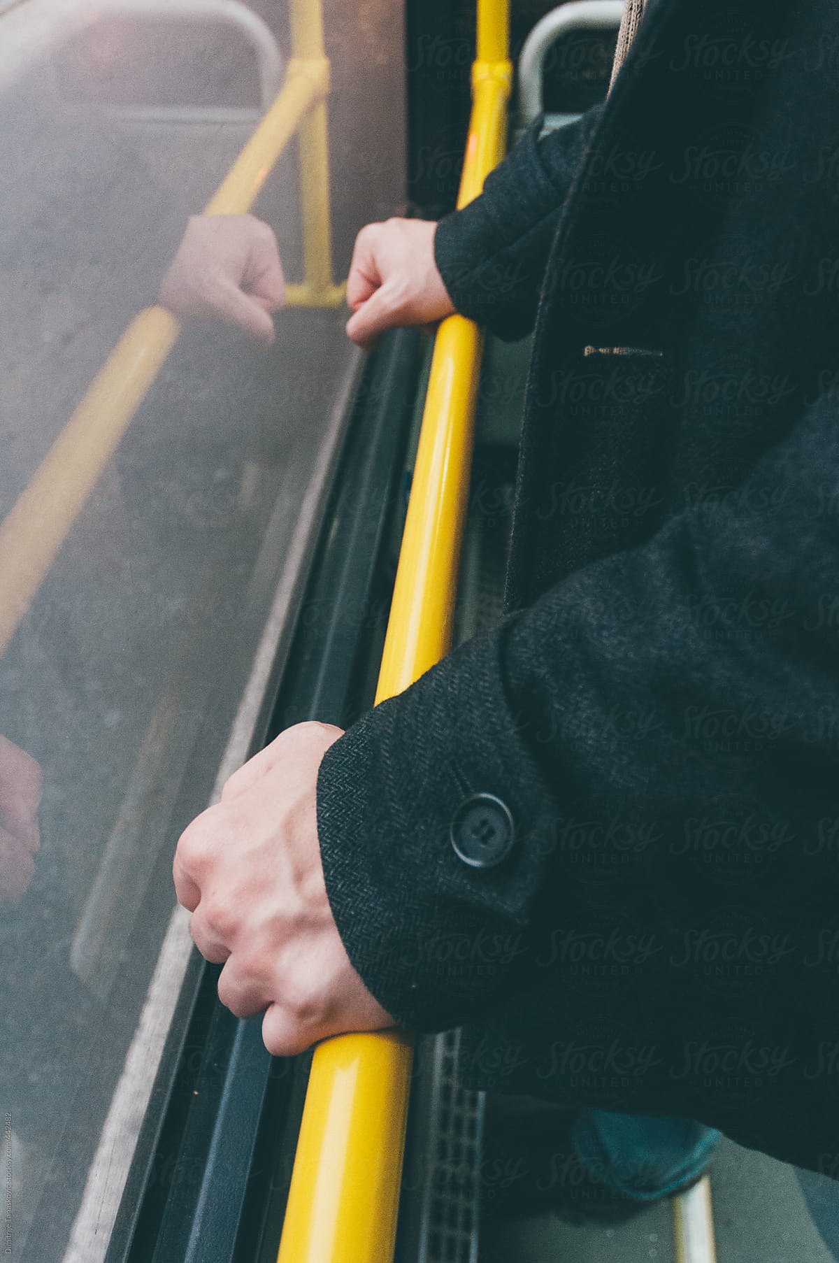 Man holding for yellow pole in public transport