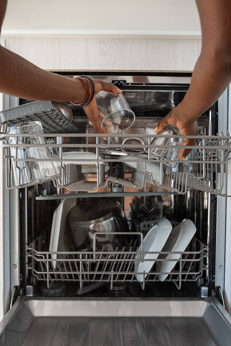 Crop female arranging glassware in dishwasher