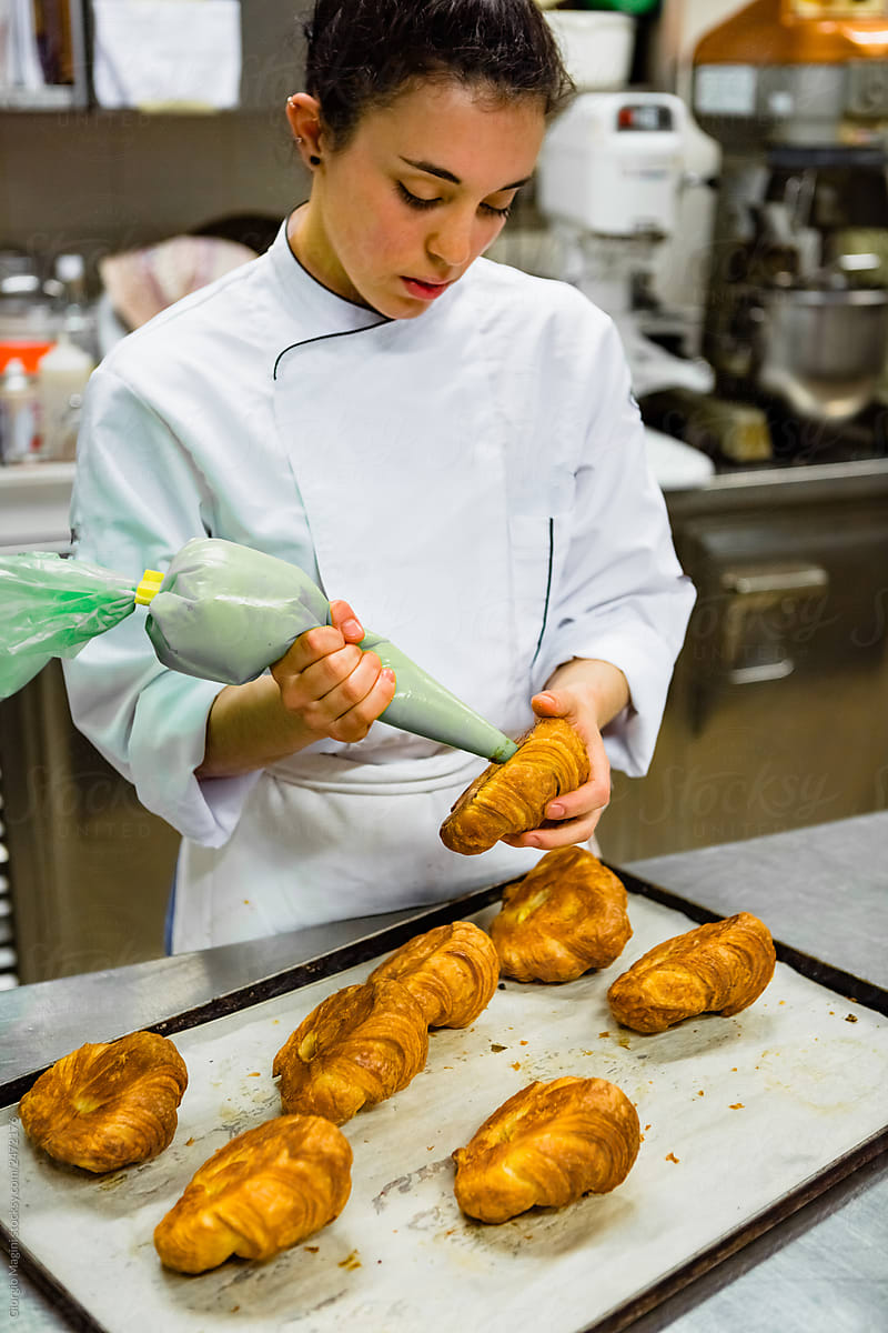 Young Pastry Chef Filling Croissants with Cream