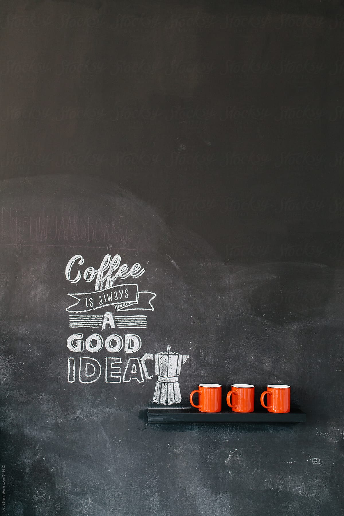 'Coffee is always a good idea' quote written on a blackboard, with red cups next to it