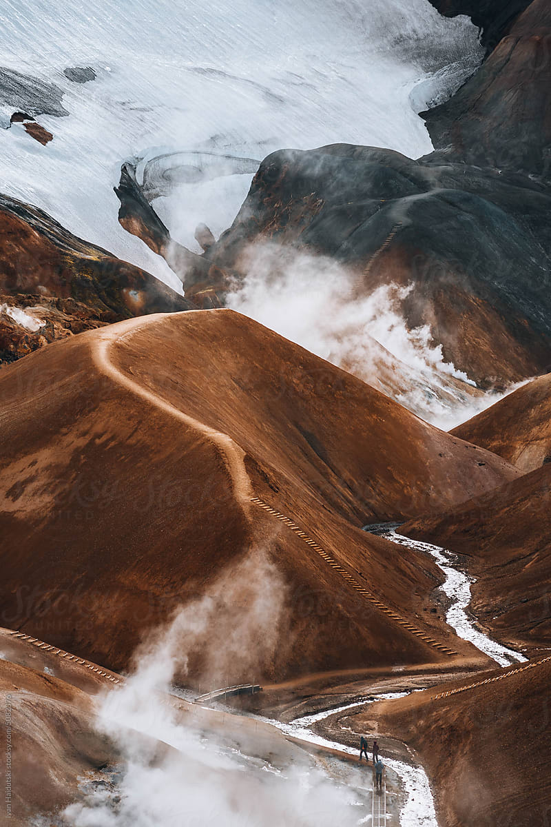 Hiker exploring golden brown landscape of Iceland's geothermal area.