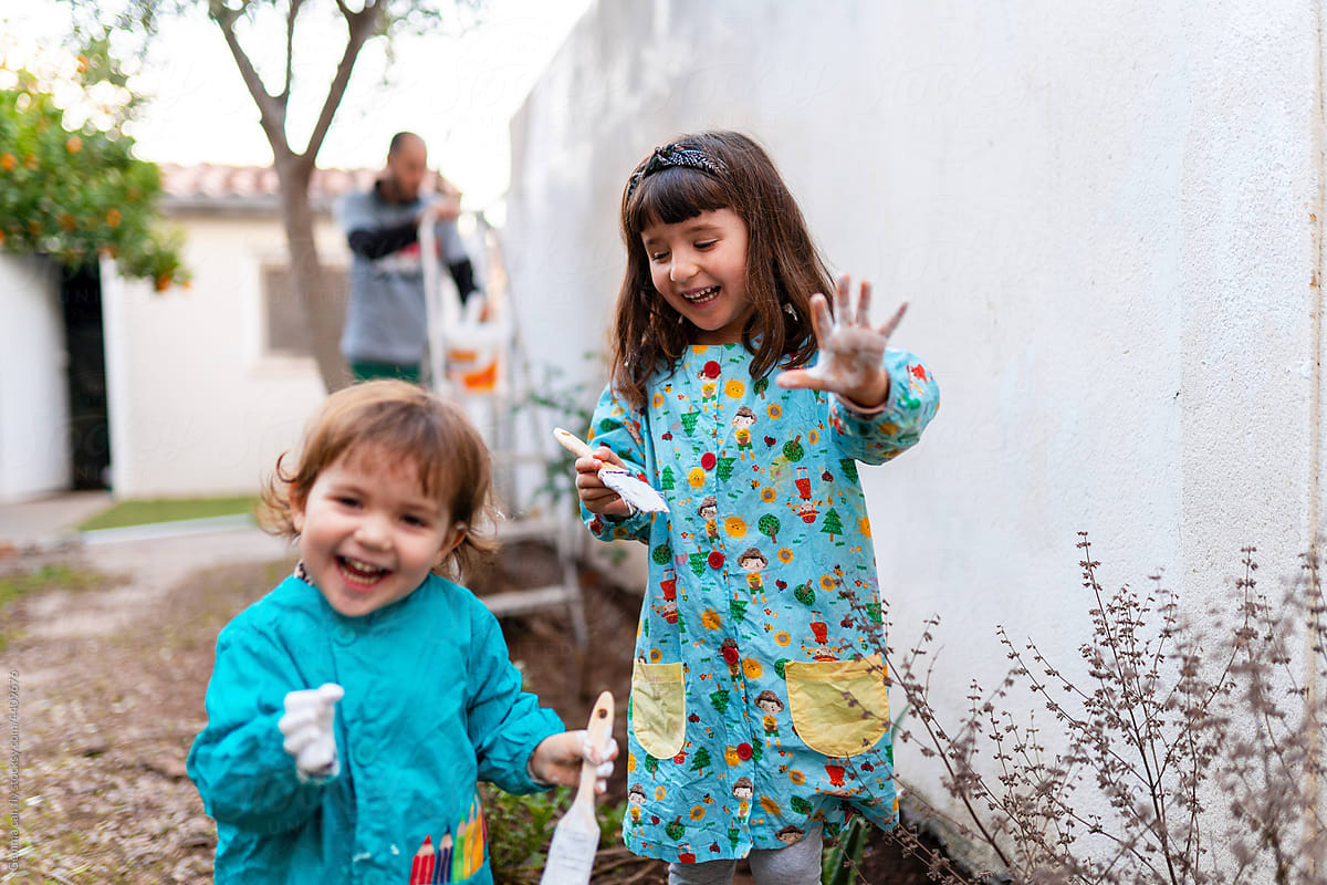 Happy sisters painting backyard