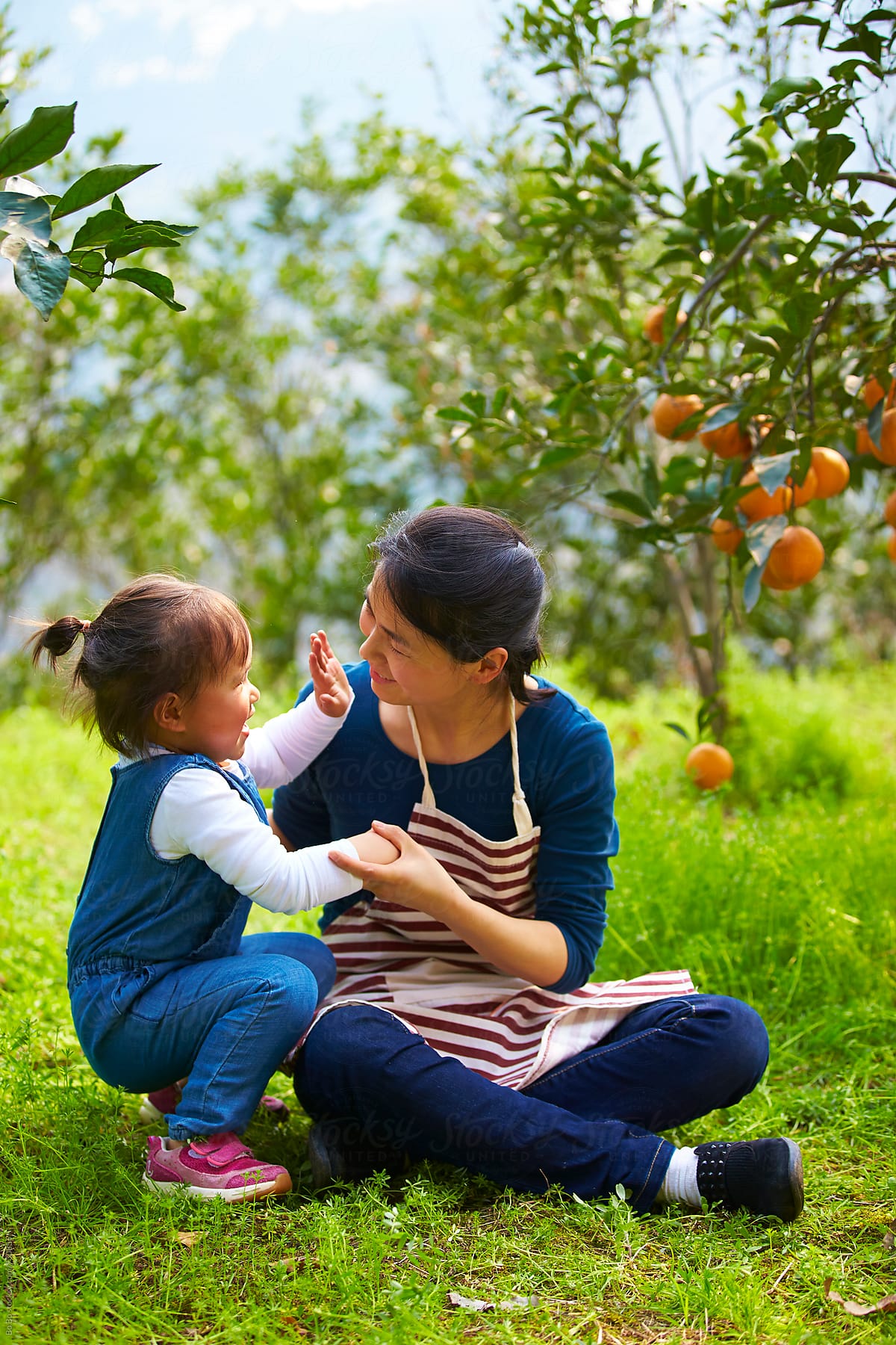 happy asian mother with her daughter in the orange farm