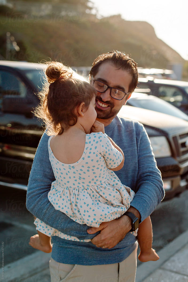 Happy dad holding daughter in parking lot