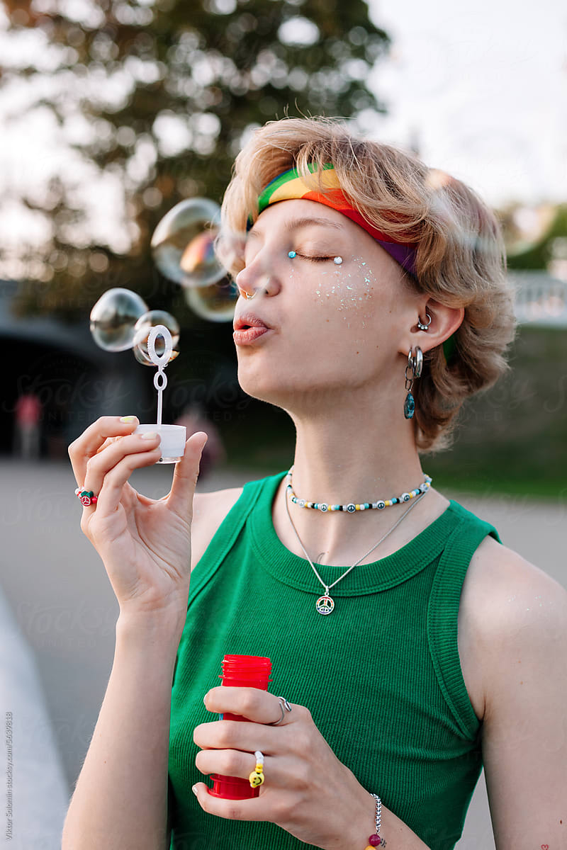 Queer Pansexual Woman blowing bubbles in park