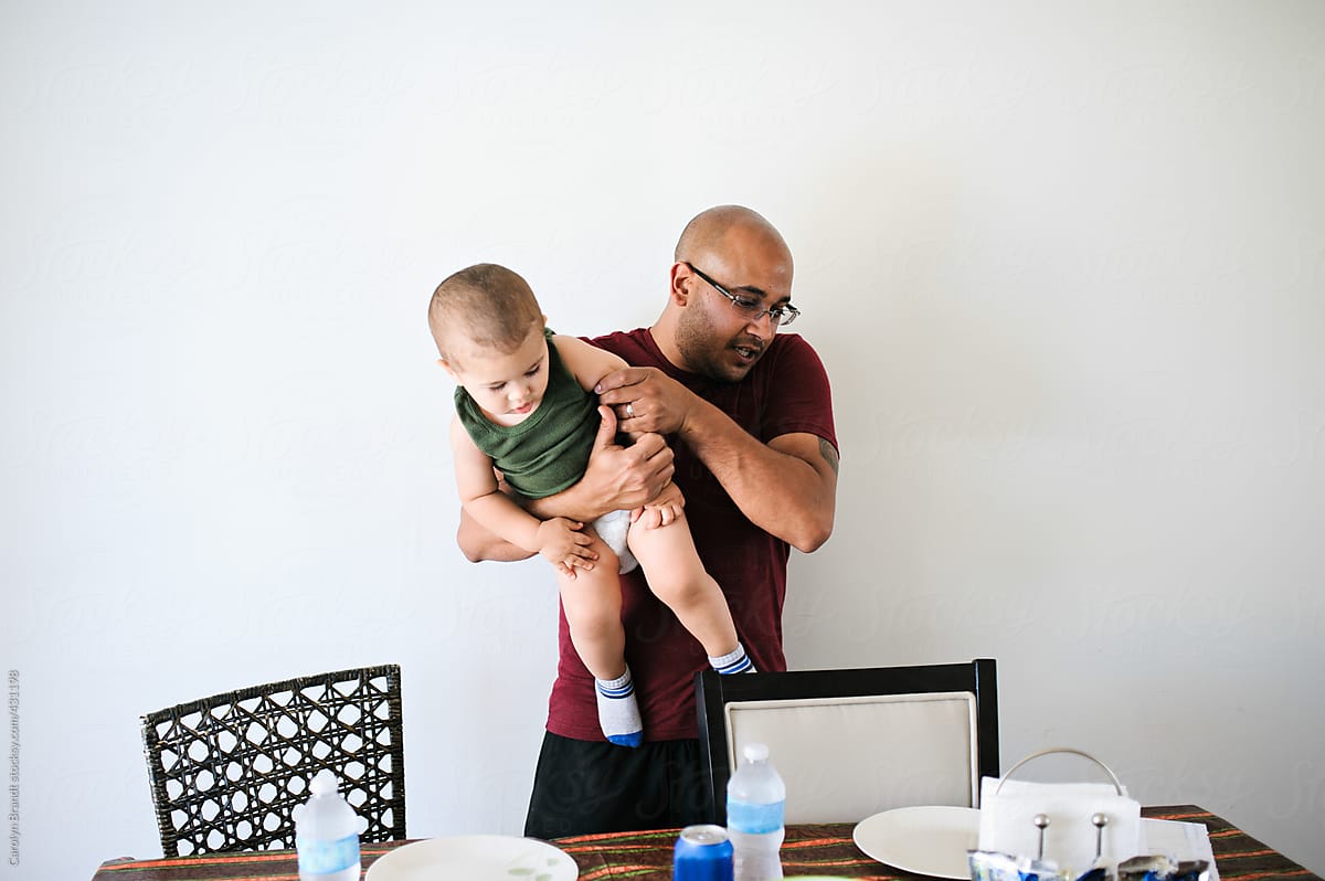 Father lifting son at dinner table