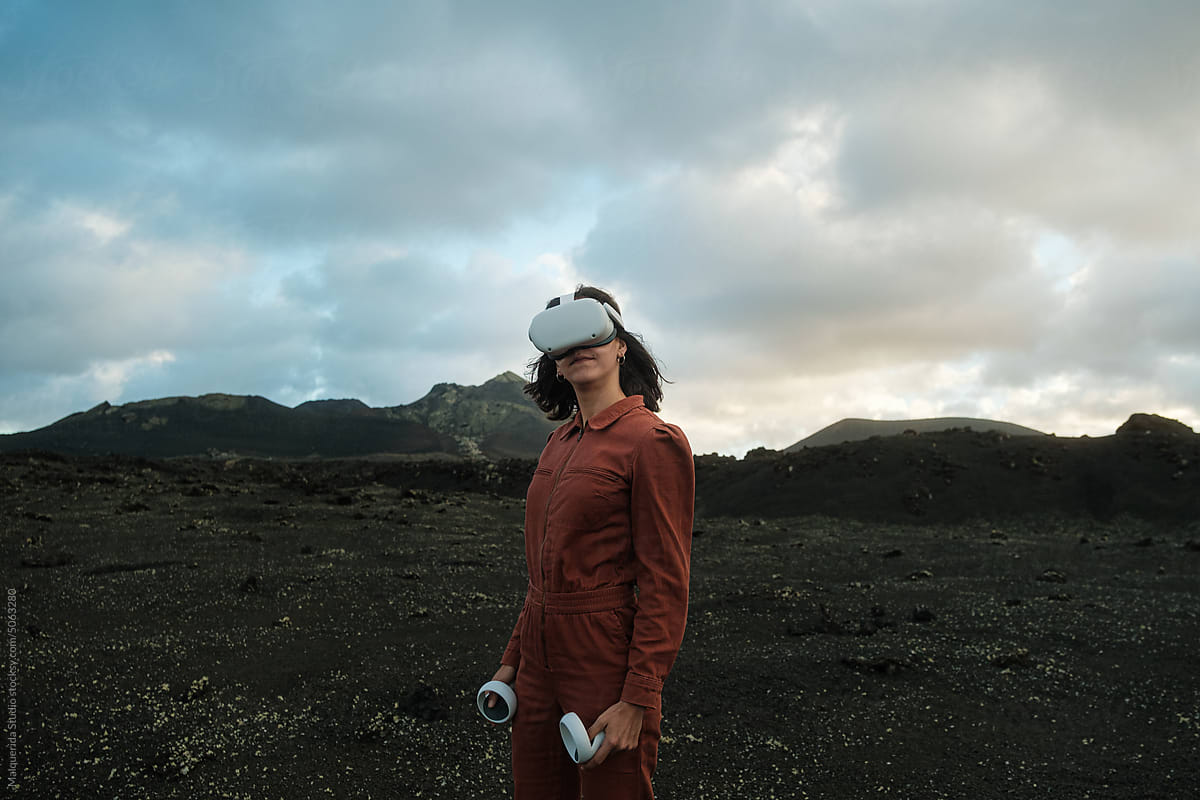Woman with VR glasses and joysticks in volcanic scenery