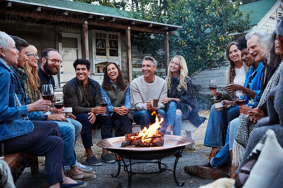 Multigenerational group of friends and family at fire outdoors