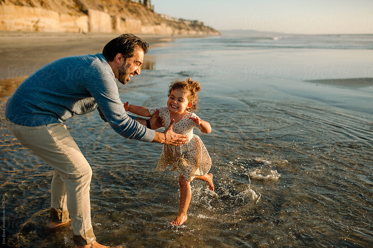 Father lifts joyful daughter from ocean