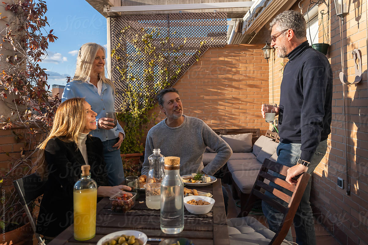 Adult Friends Talk Happily In A Gathering On A Terrace