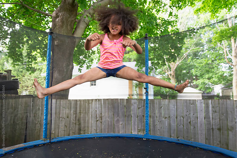 A Young Girl Jumping In A Large Trampoline.
