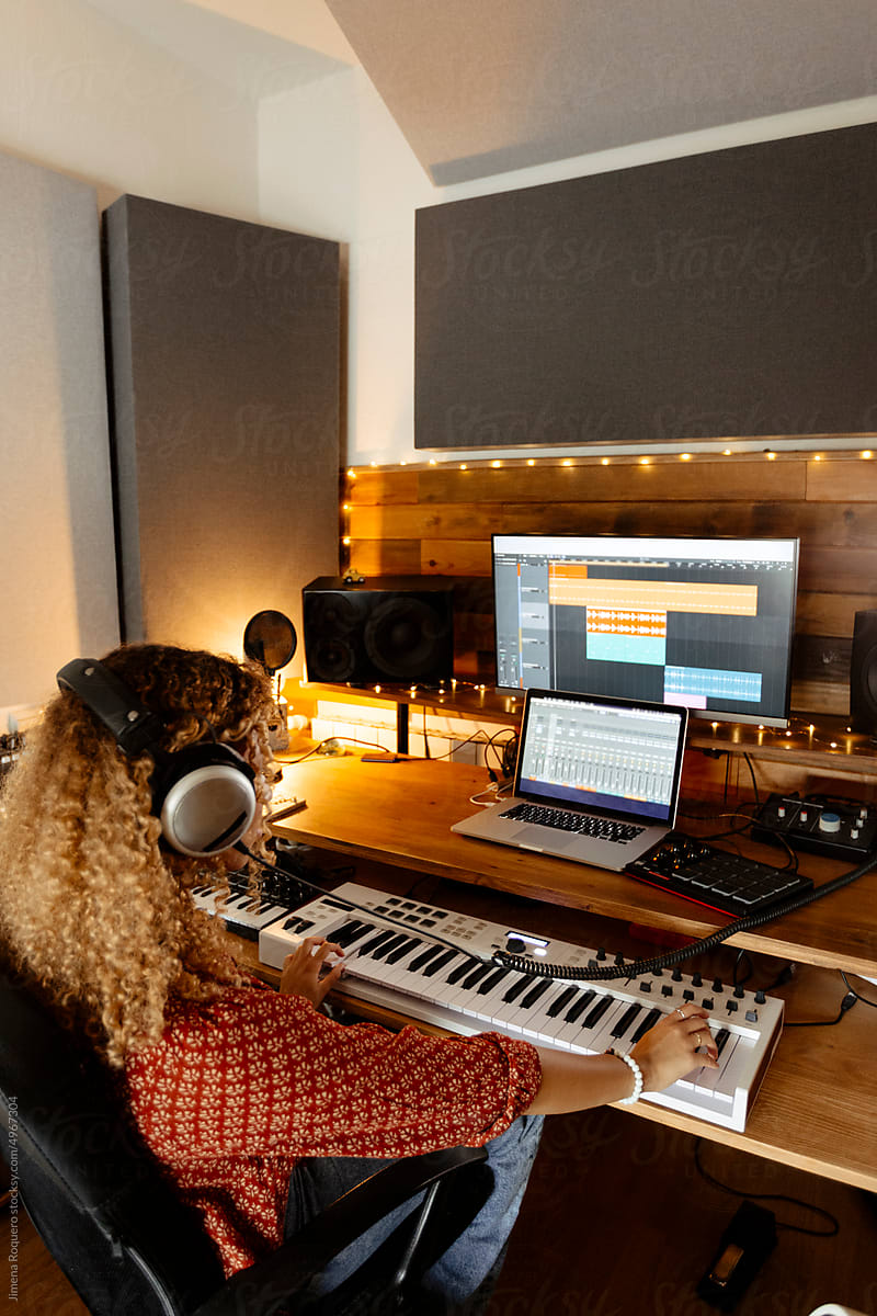 Music producer at home studio using keyboard controller from the back