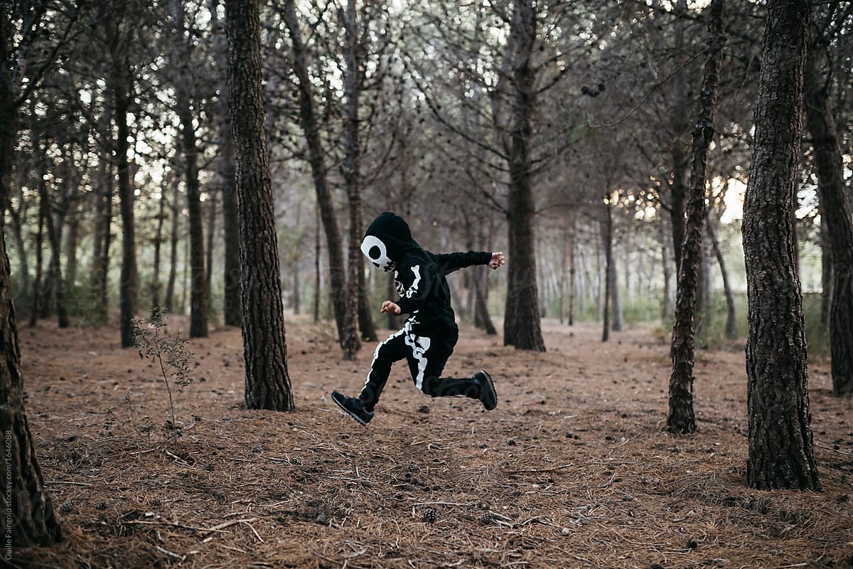 Boy in halloween costume running in forest.