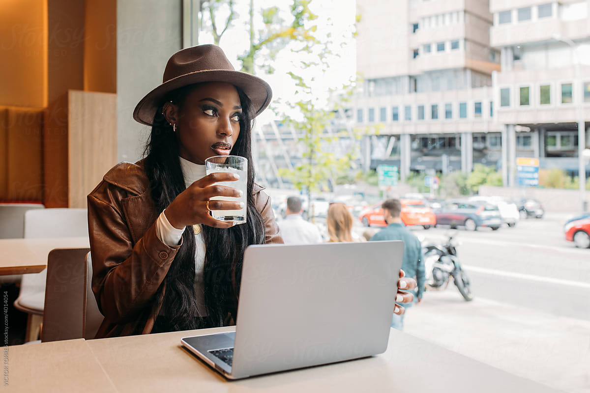 Black woman with laptop and lemonade sitting in cafe