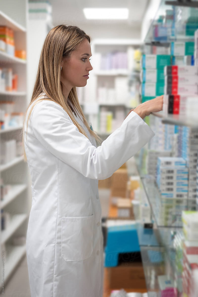 Pharmacist searching drug on shelf